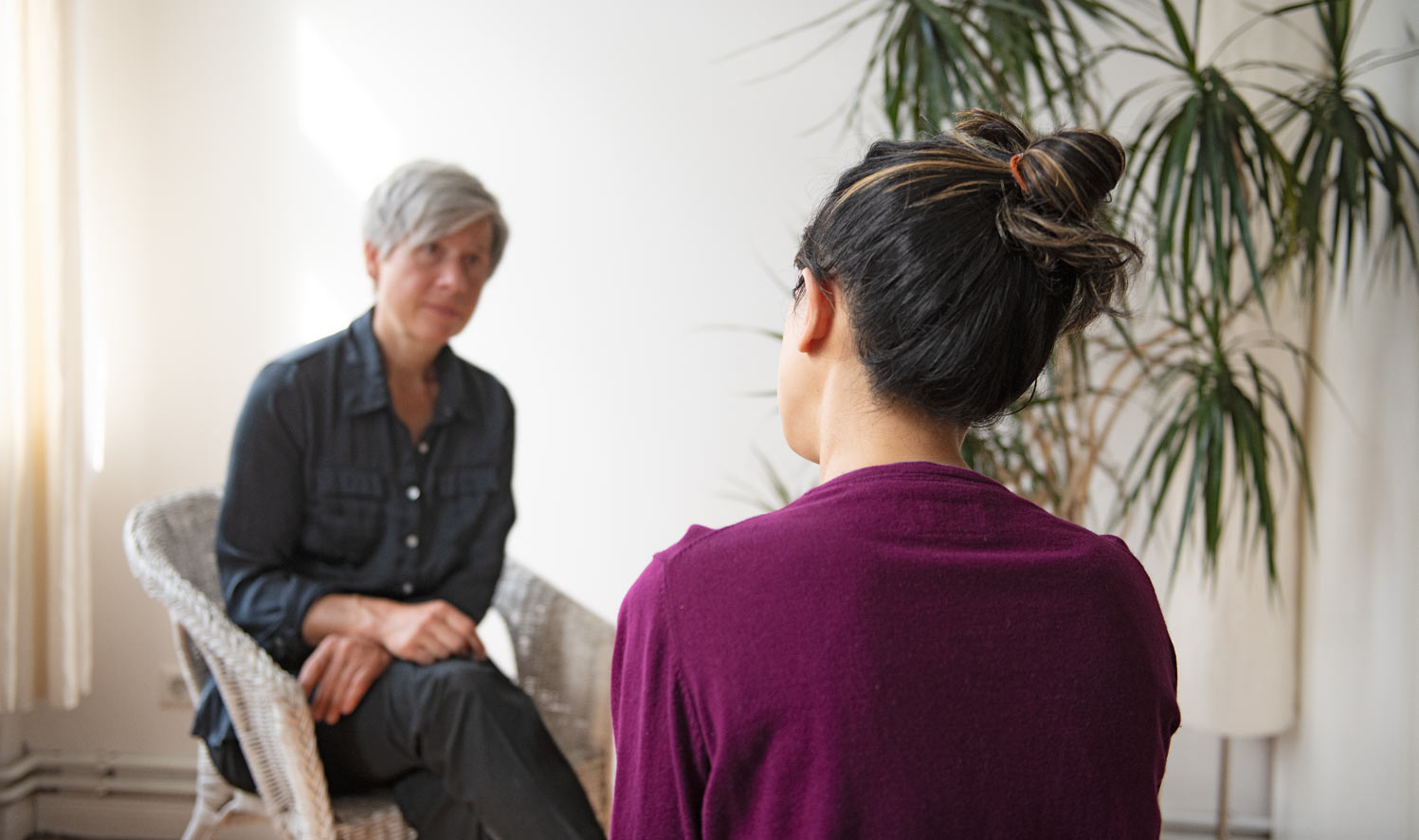 Zwei Frauen sitzen in einer Therapiesitzung gegenüber und sprechen miteinander