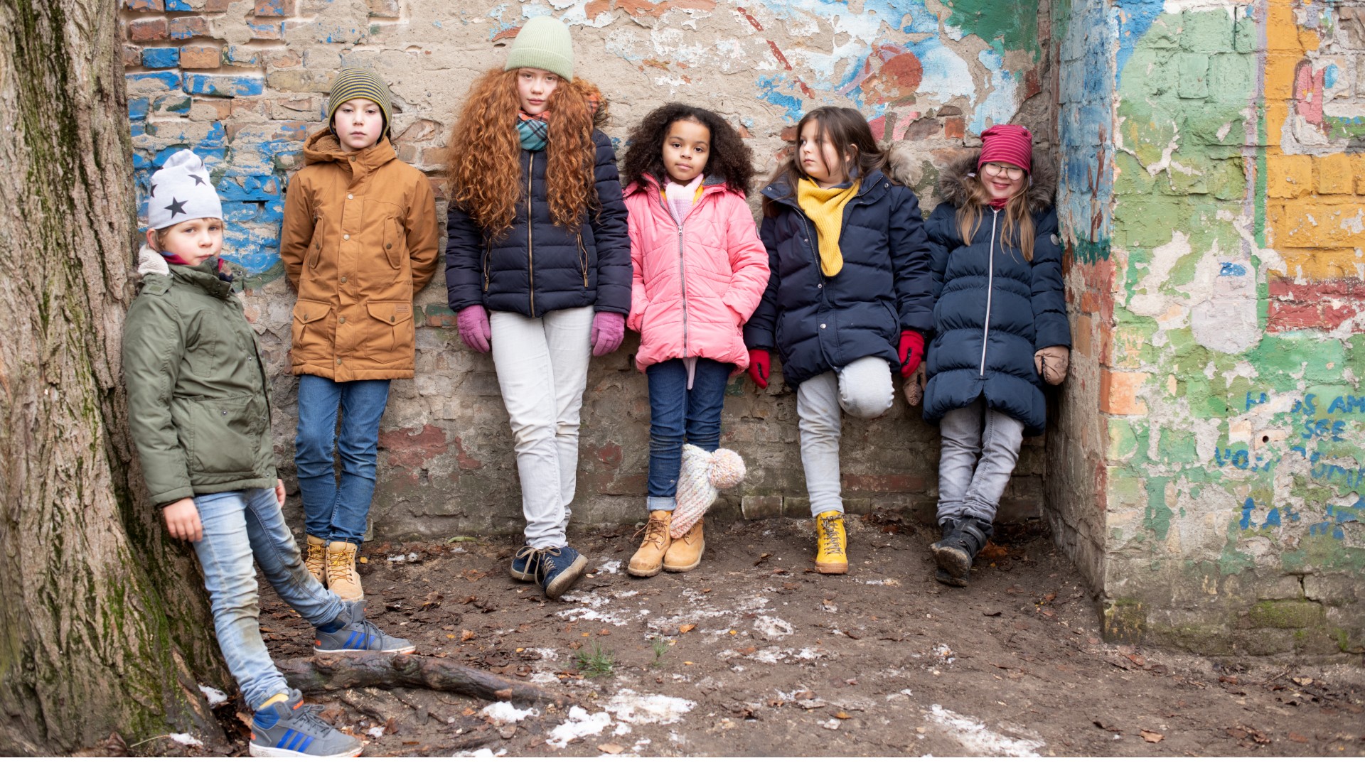 Gruppe von Kinder und Jugendlichen vor einer besprayten Wand