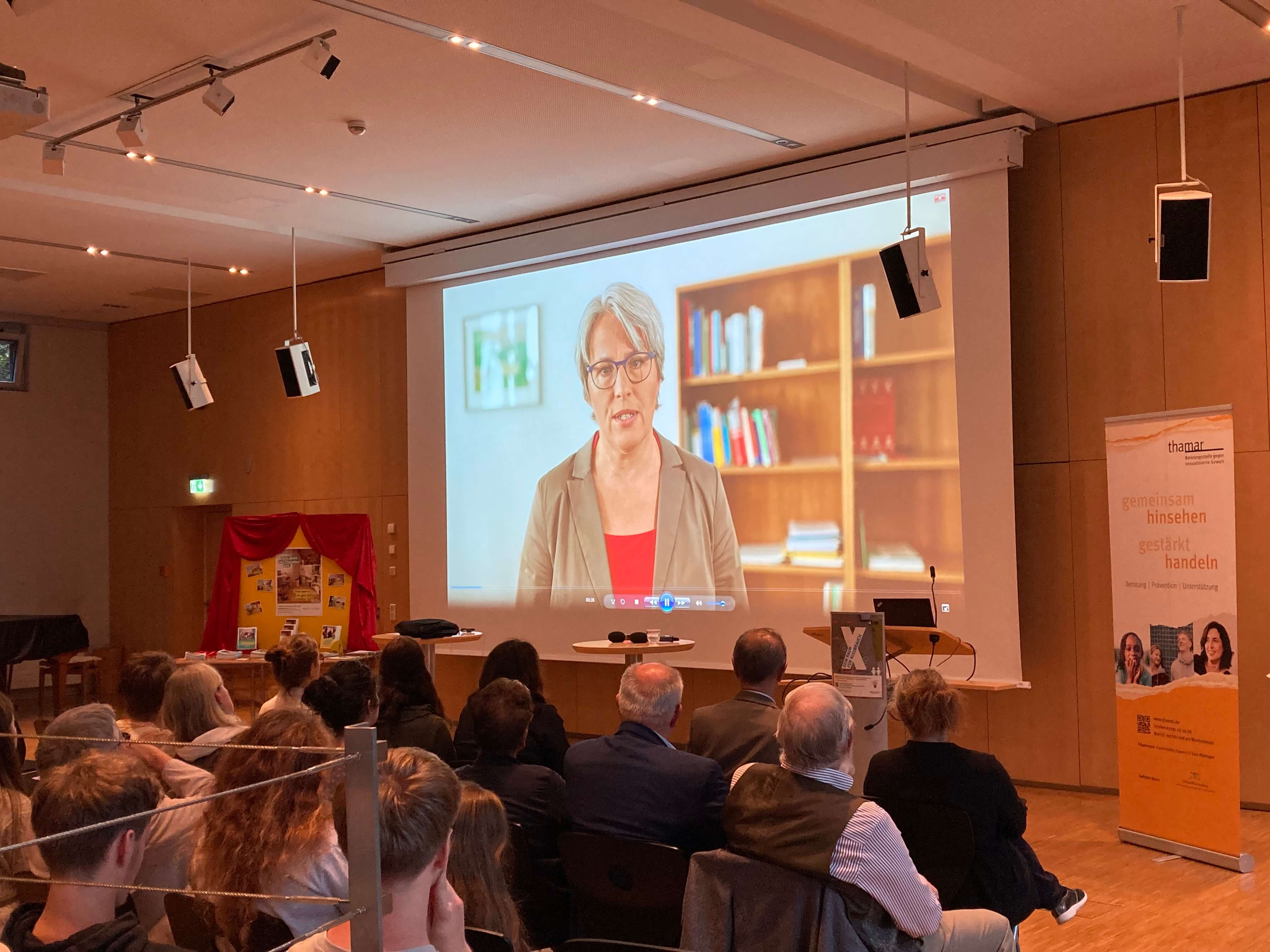 Teilnehmende sitzen vor einer Leinwand