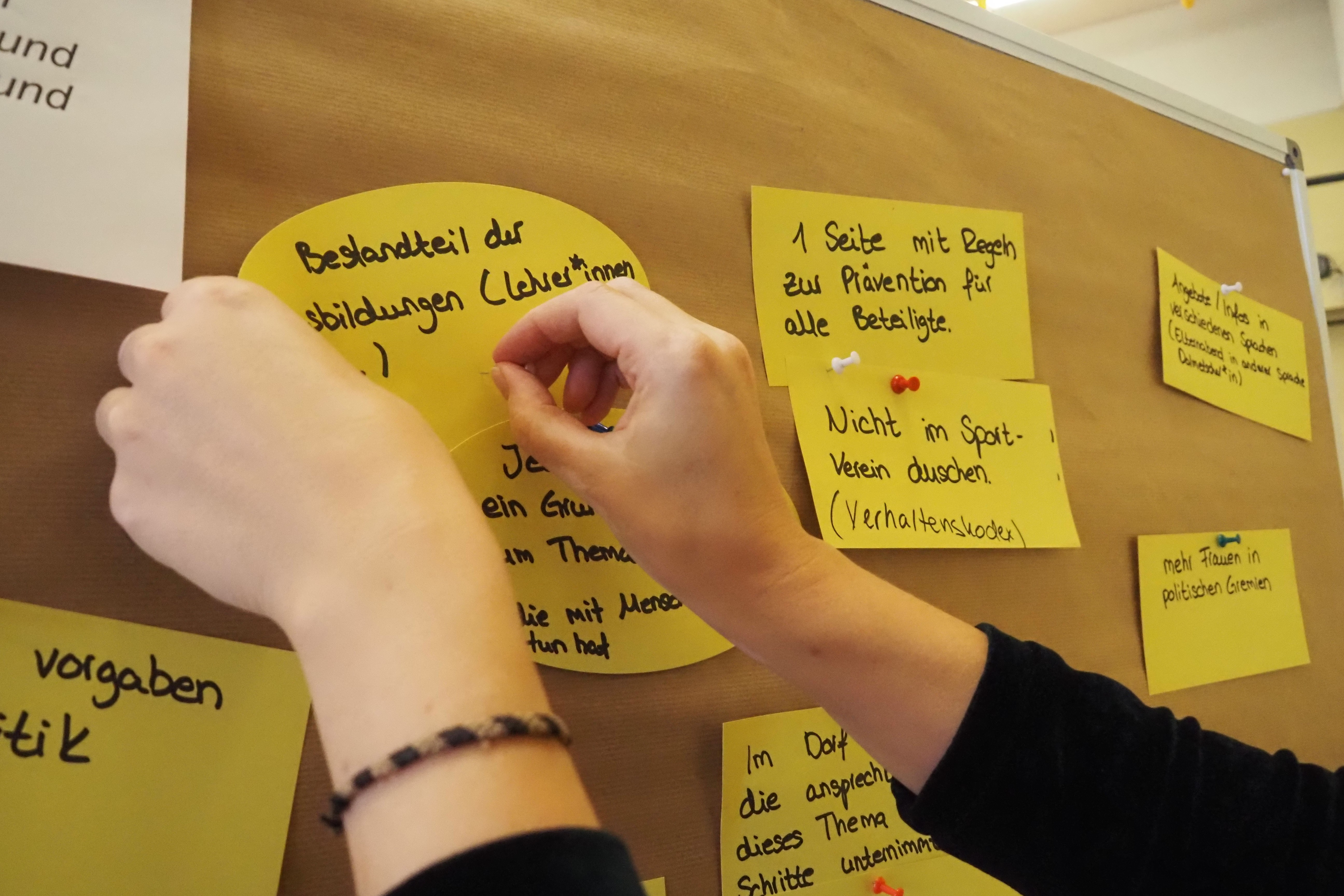 Hände, die Post-It´s an ein Whiteboard kleben.