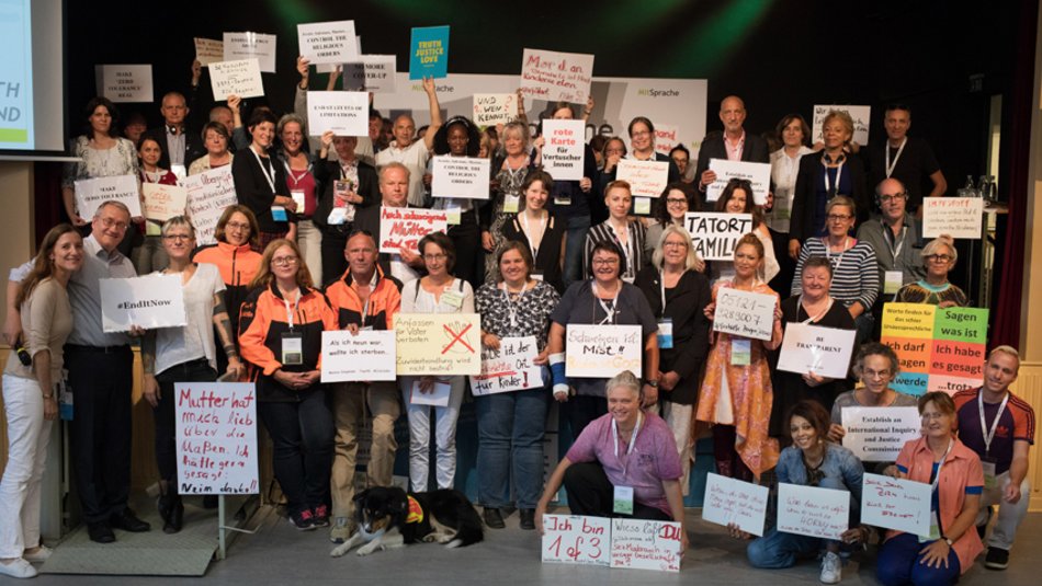 Das Foto zeigt ein Gruppenbild von Teilnehmenden des Kongresses "MitSprache" im Jahr 2018. Die Personen präsentieren Schilder und Plakate, auf die sie Botschaften geschrieben haben.