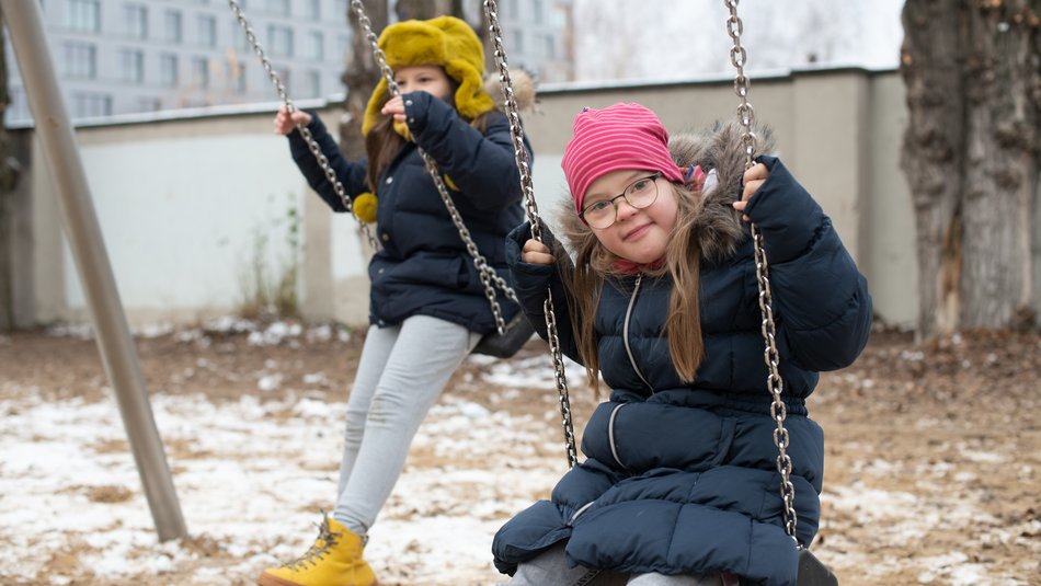 Zwei Kinder schaukeln, ein Kind schaut in die Kamera