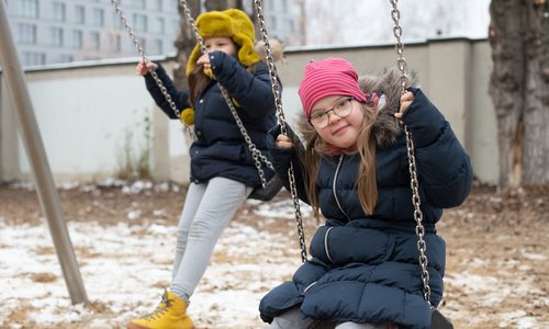 Zwei Kinder schaukeln, ein Kind schaut in die Kamera