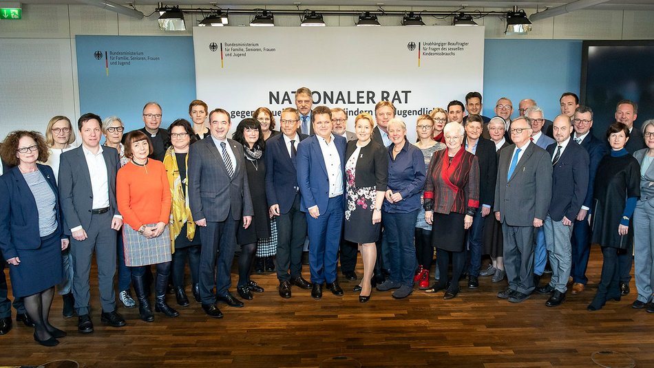 Das Foto zeigt 36 Mitglieder des Nationalen Rats gegen sexuelle Gewalt an Kinder und Jugendlichen beim gemeinsamen Fototermin anlässlich einer Sitzung. Die Vertreter:innen stehen vor einer weißen Fotowand des Nationalen Rats.