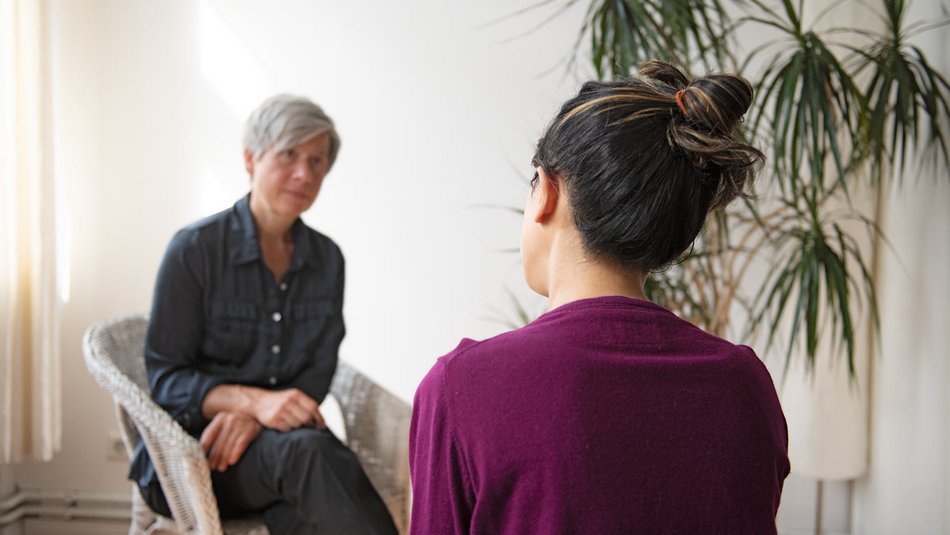 Zwei Frauen sitzen in einer Therapiesitzung gegenüber und sprechen miteinander